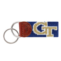 Navy needlepoint key fob with the gold Georgia Tech interlocking “GT” logo, brown leather trim, and a metal key ring.