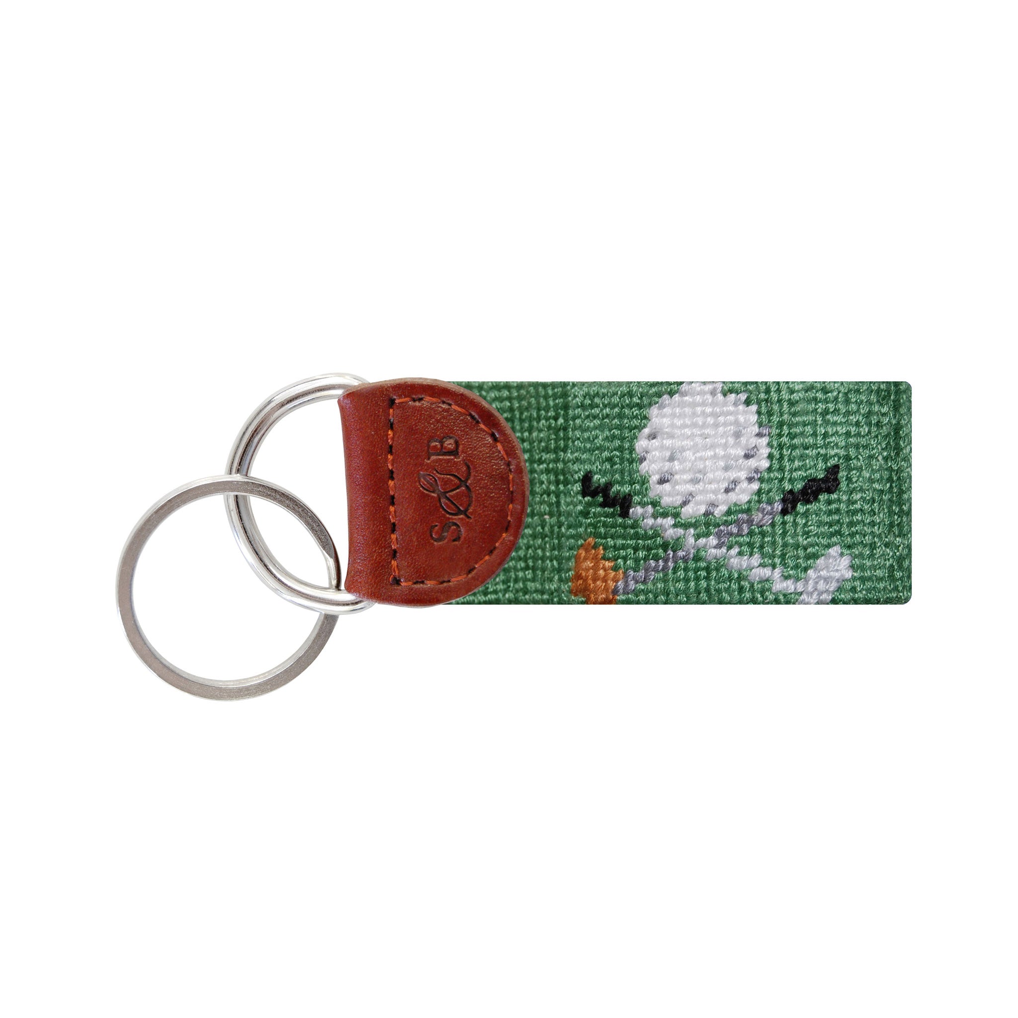 Sage green needlepoint key fob featuring crossed golf clubs, brown leather trim, and a metal key ring.