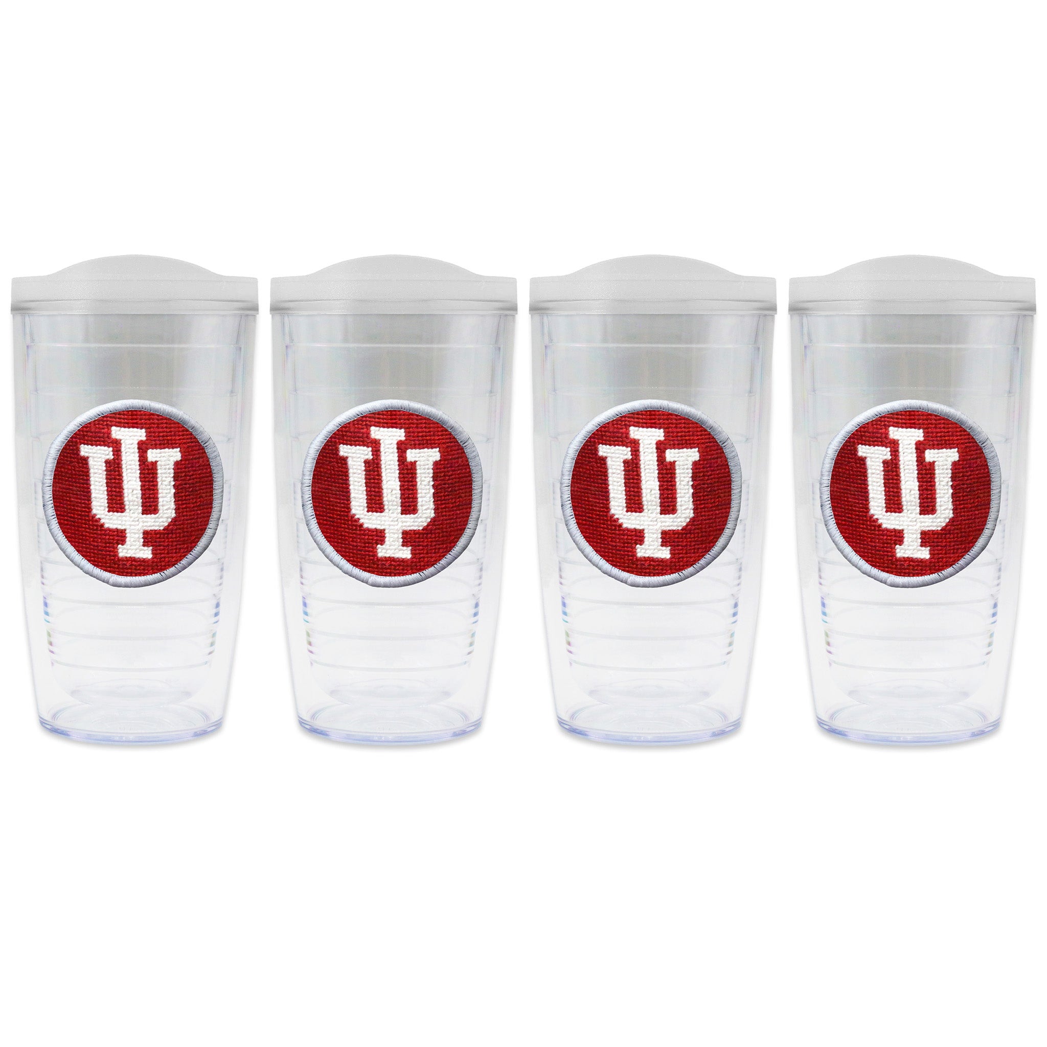 Set of 4 tumblers with lids on each in a line with a needlepoint logo in the center of each tumbler