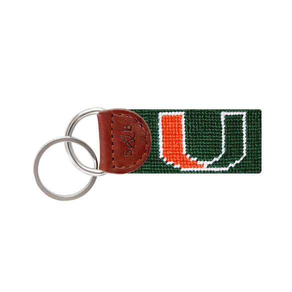 Dark green needlepoint key fob featuring the orange and green Miami “U” logo, brown leather trim, and a metal key ring.