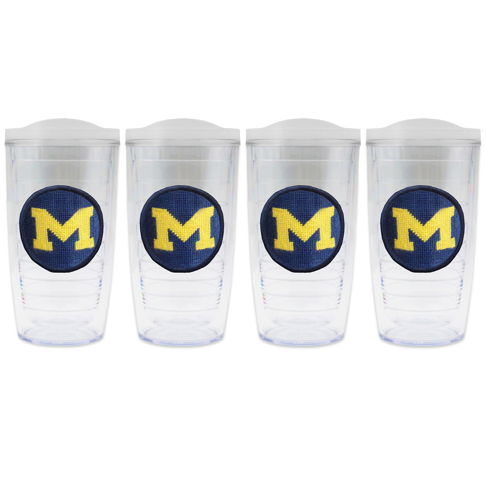 Set of 4 tumblers with lids on each in a line with a needlepoint logo in the center of each tumbler