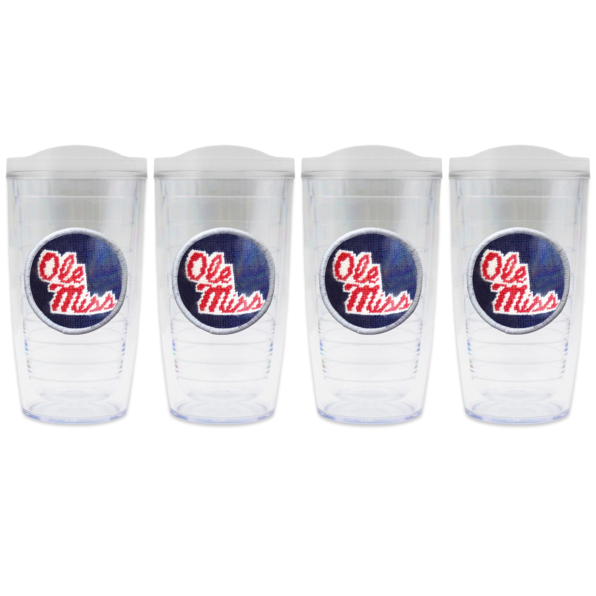 Set of 4 tumblers with lids on each in a line with a needlepoint logo in the center of each tumbler