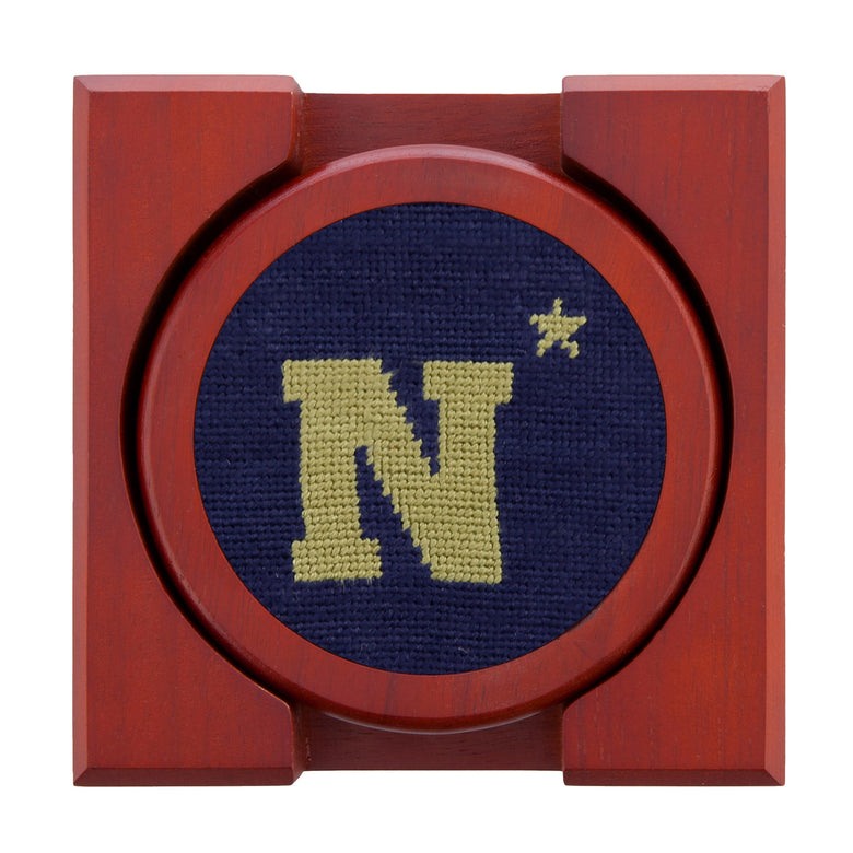 Navy needlepoint coaster set showing the Navy “N” logo on one and matching navy-and-gold themes on others, backed with chestnut wood.