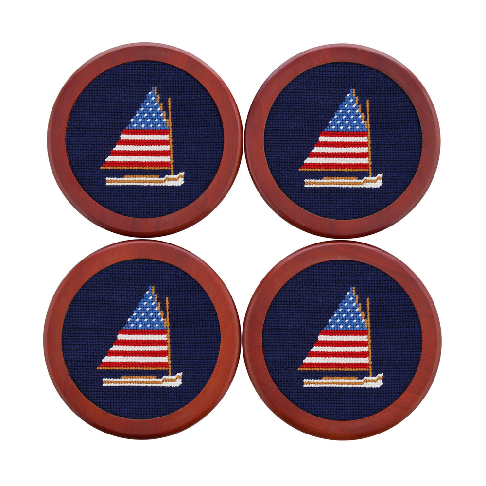 Four coasters with embroidered sailboat design on a blue background