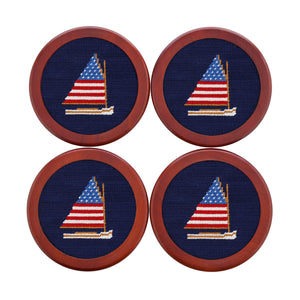 Four coasters with embroidered sailboat design on a blue background