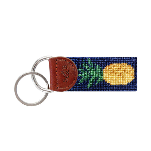 Sky blue needlepoint key fob with a yellow pineapple design, brown leather trim, and a metal key ring.