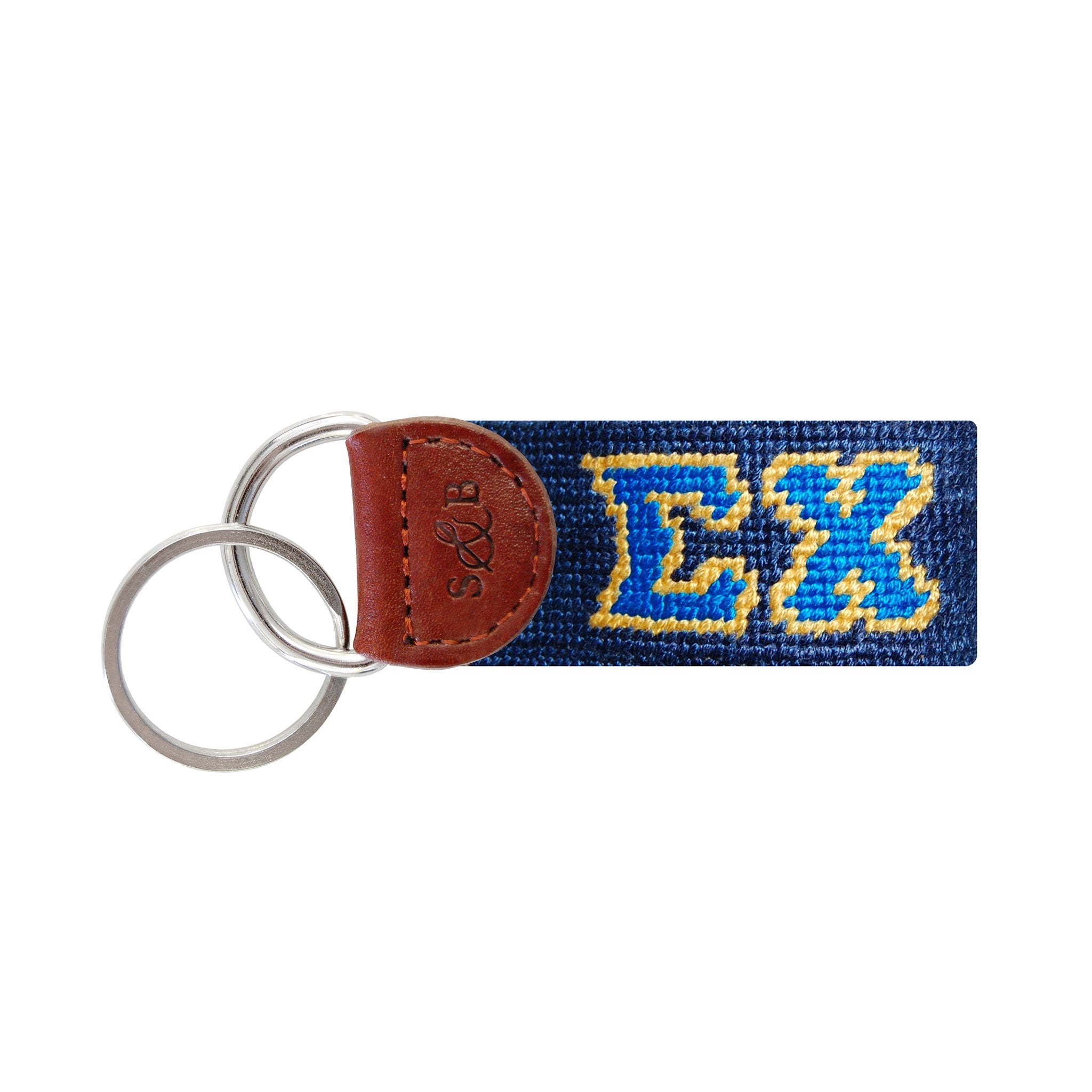 Navy needlepoint key fob with the gold Sigma Chi crest, brown leather trim, and a metal key ring.