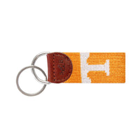 Bright orange needlepoint key fob featuring a white "Power T" logo, brown leather trim, and a metal key ring.