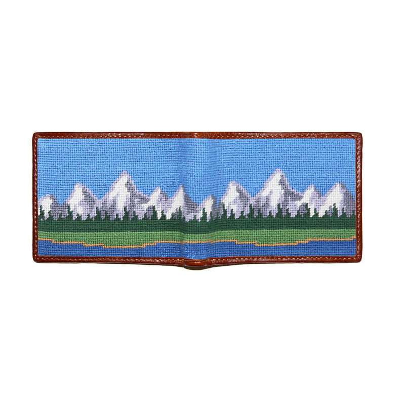 Multi-color mountain landscape needlepoint bi-fold wallet open to show both sides of the design with brown leather trim.