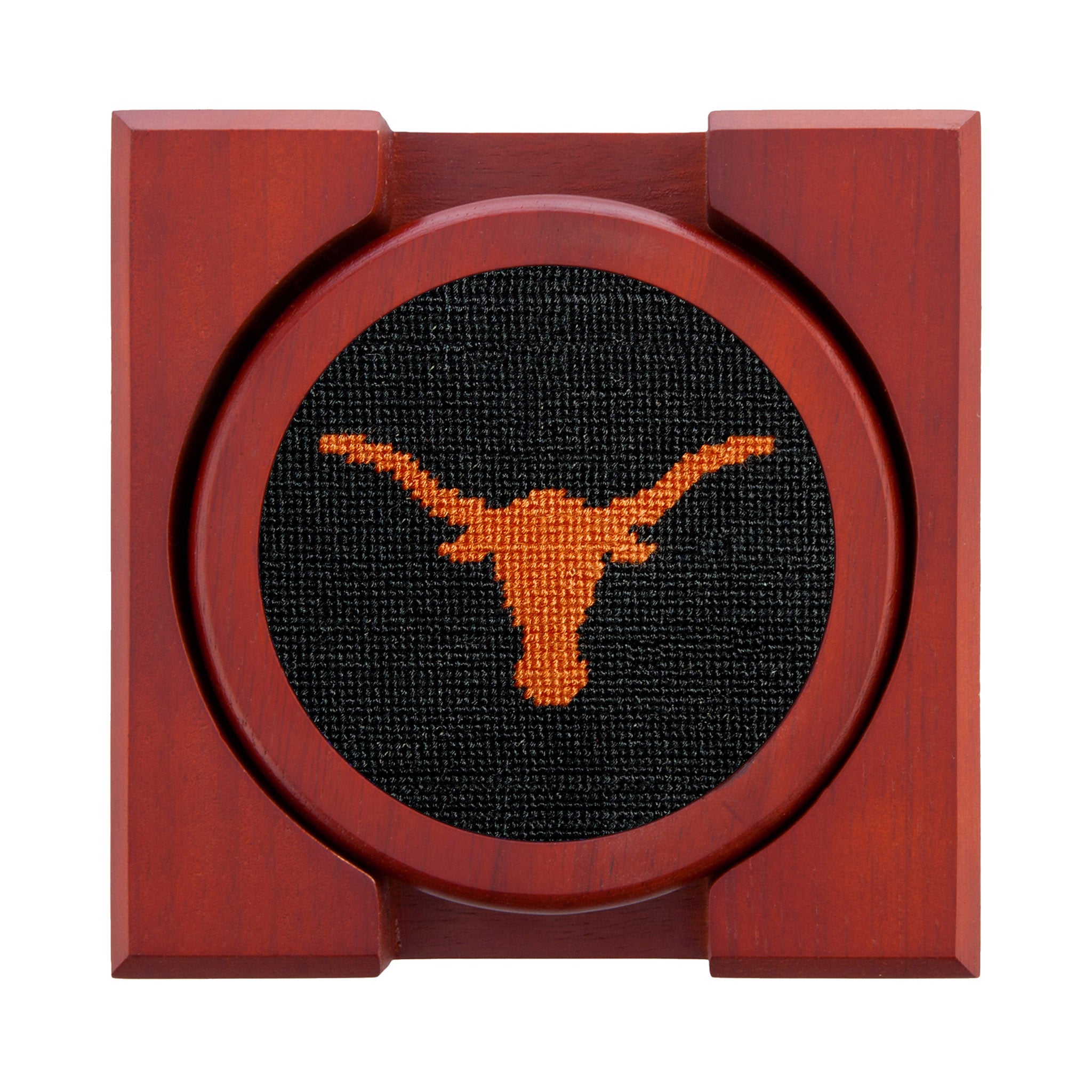 Set of four round wooden coasters with stitched needlepoint logos stacked neatly in a wooden holder.