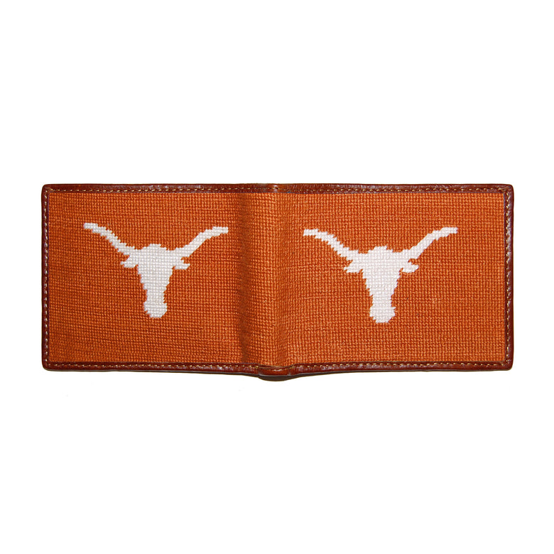 Texas burnt orange needlepoint bi-fold wallet open to show both sides of the white “Texas” text needlepoint design with brown leather trim.