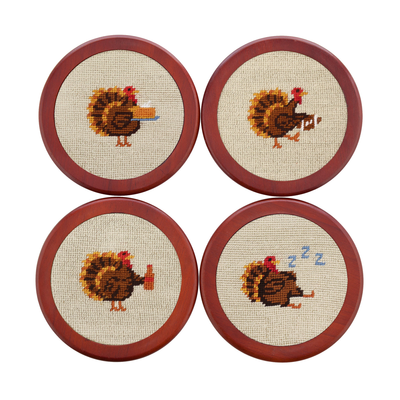 Light khaki coasters featuring colorful Thanksgiving-themed drinks stitched in needlepoint, shown laid flat.