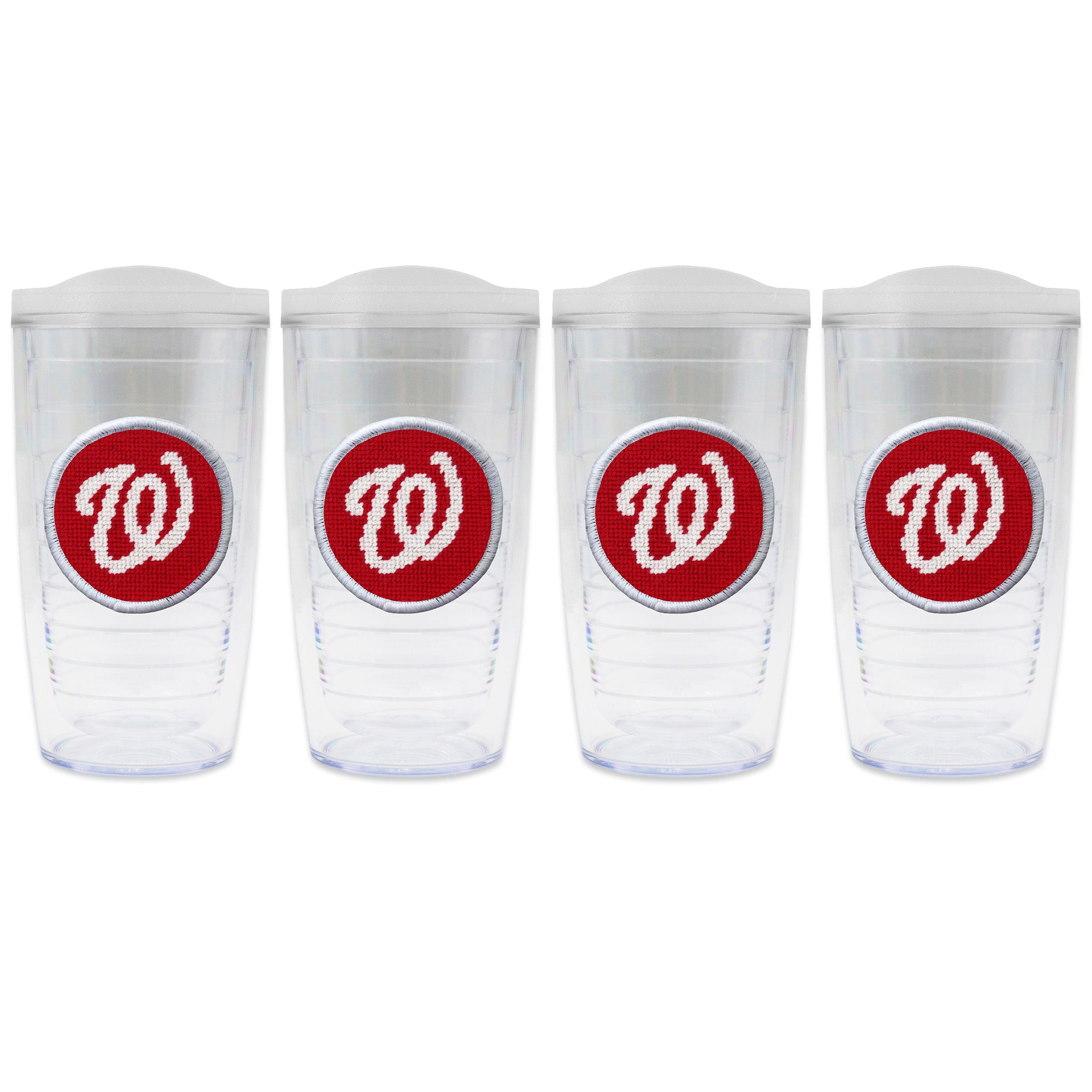 Set of 4 tumblers with lids on each in a line with a needlepoint logo in the center of each tumbler