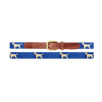 Children’s belt laid flat to show the full stitched design of yellow lab dogs on a blueberry needlepoint background, finished with brown leather ends and a brass buckle.
